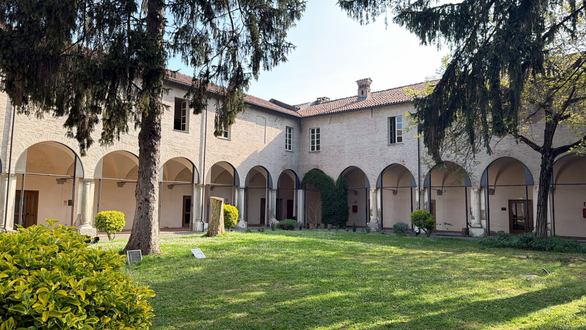 Persone di generazioni diverse sedute in cerchio nel cortile di un chiostro, in ascolto